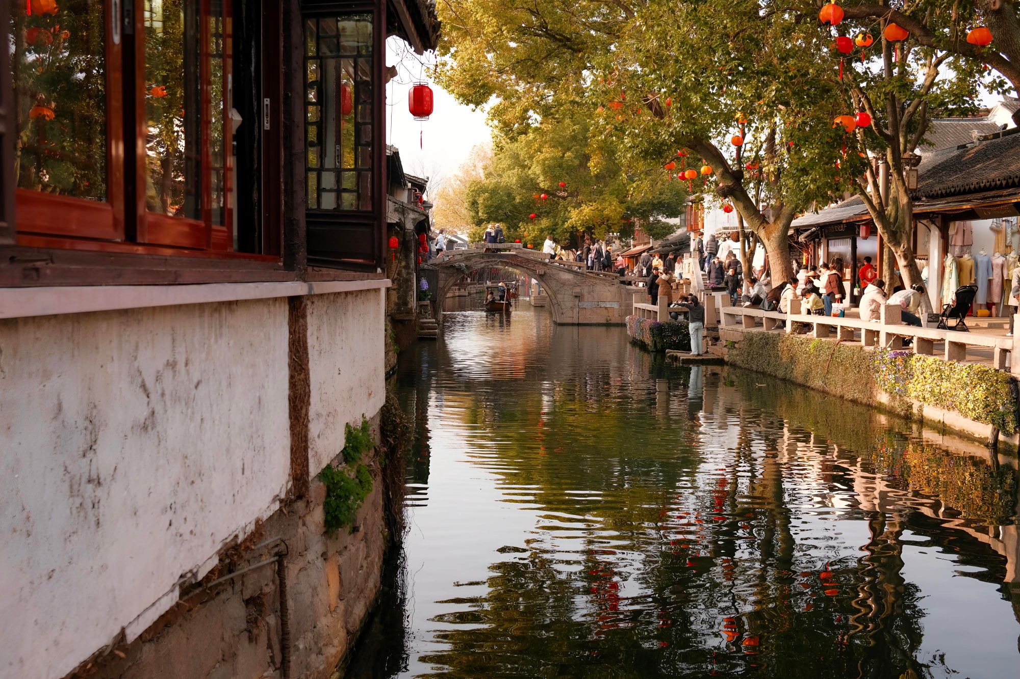 A historic canal in Suzhou lined with red lanterns and traditional houses